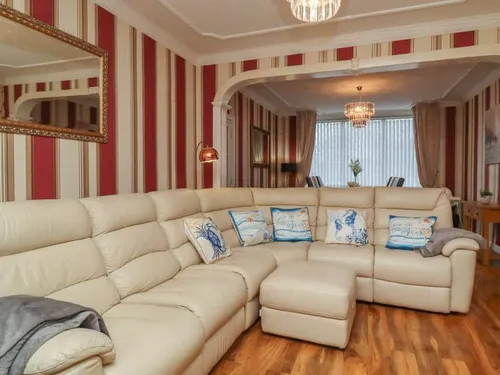 Cottage living room with cream corner sofa and striped wallpaper