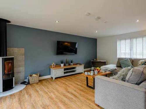 Cottage living room with wood burner, TV and grey corner sofa
