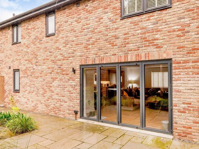 Brick exterior of cottage with large patio doors leading to garden area
