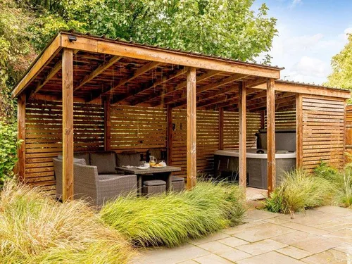 Covered patio seating area with hot tub in cottage garden