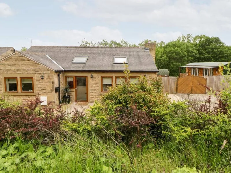 2 Pheasant Lane stone cottage with skylights and garden shrubs in the foreground