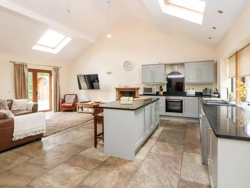 Cottage kitchen with island and adjoining lounge area with sofa and TV