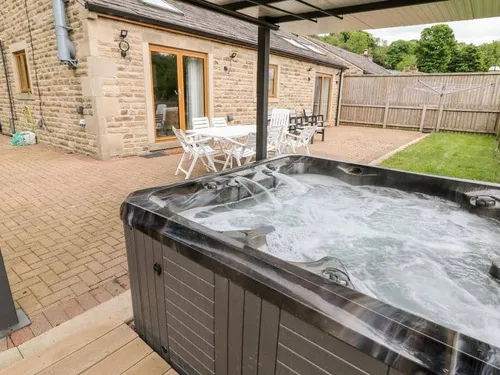 Cottage patio with outdoor hot tub and white dining table