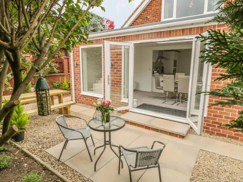 Abbey View cottage patio with round glass table, chairs and open bi-fold doors