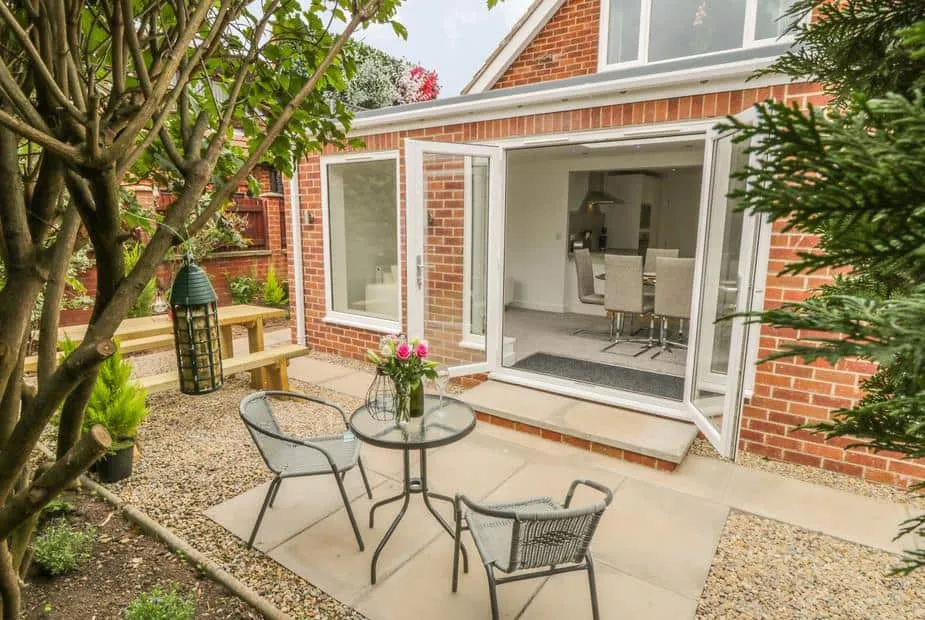 Abbey View cottage patio with round glass table, chairs and open bi-fold doors