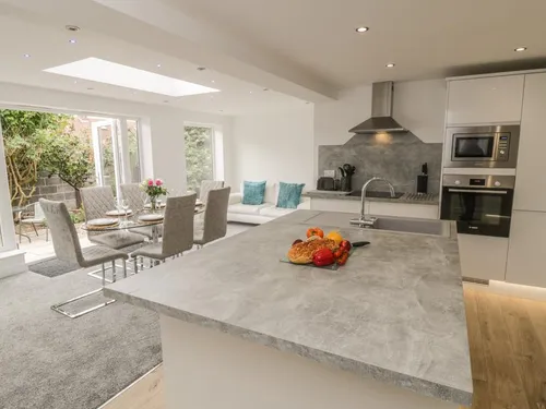 Spacious open-plan kitchen with central island and dining area opening onto private garden