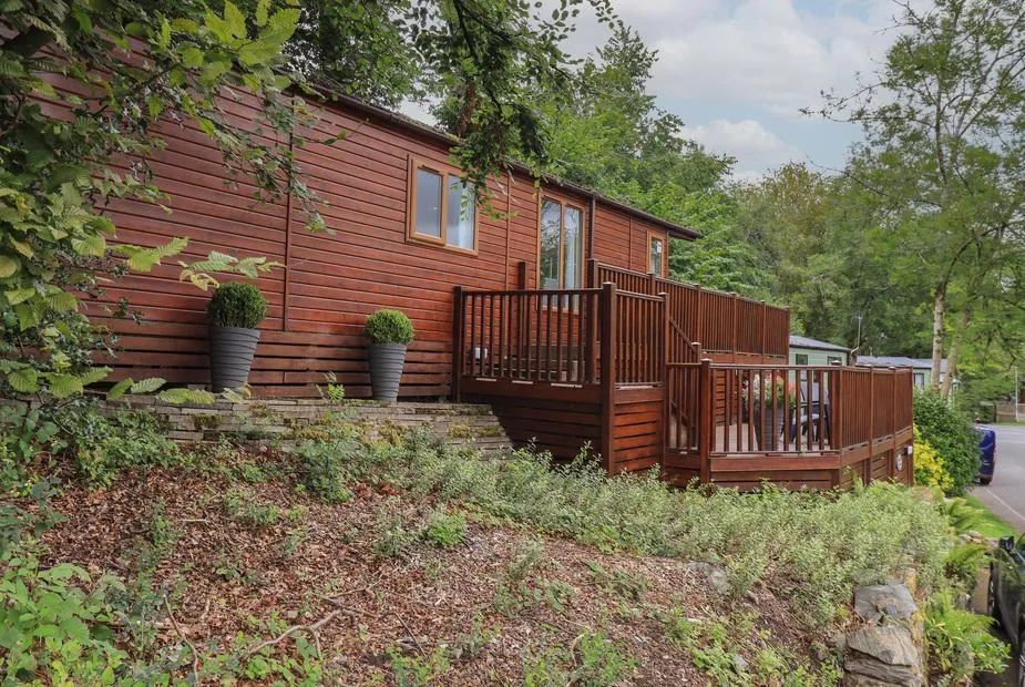 Acorn Bank Lodge with raised deck surrounded by trees and potted plants