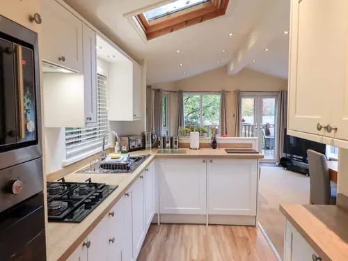 Lodge kitchen with gas hob, oven and skylight, leading into open-plan living area