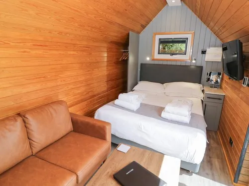 Lodge interior with double bed, sofa, and wall-mounted television