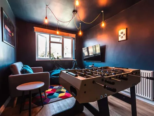 Cottage games room with table football, sofa and wall-mounted TV