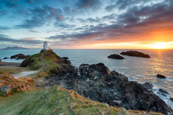 Golden sunset reflecting on the sea, with the historic lighthouse on Llanddwyn Island.