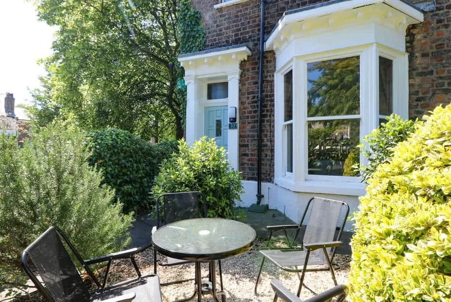Baggergate House front garden with glass table and chairs surrounded by greenery