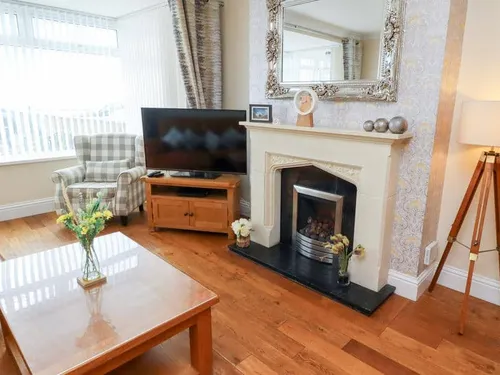 Cottage living room with fireplace, television, armchair and wooden coffee table