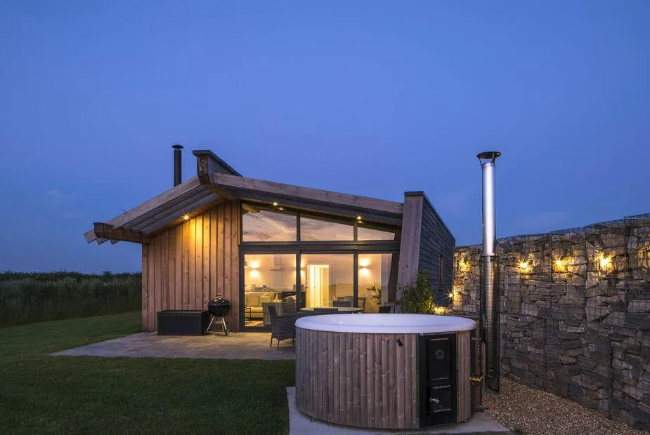 Lodge with outdoor hot tub and stone feature wall at dusk
