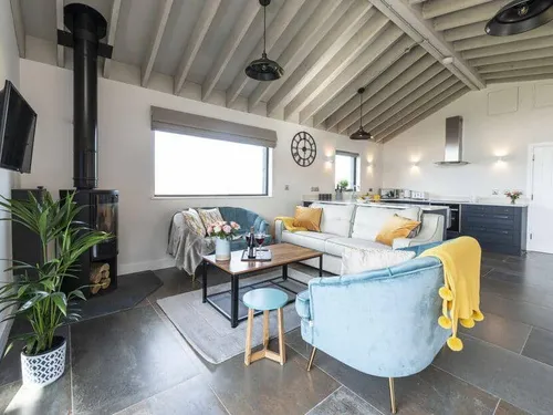 Lodge open-plan living area with wood-burning stove, sofa, and kitchen in background
