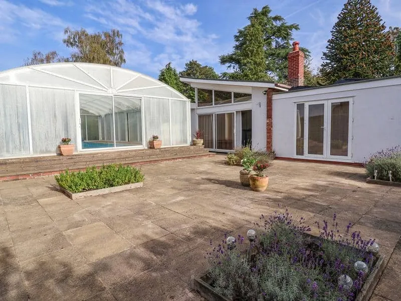 Bramble Lodge with paved patio and enclosed swimming pool visible in the garden.