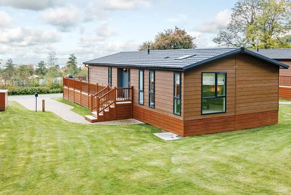 Lodge with decking surrounded by grass and trees