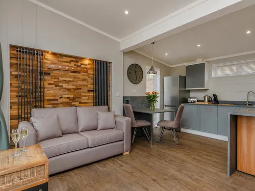 Lodge living area with sofa, wood panel feature wall and open-plan kitchen