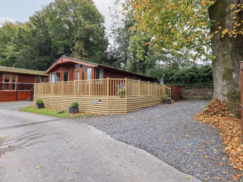 Buttermere Lodge with decked veranda beside a large tree and gravel driveway