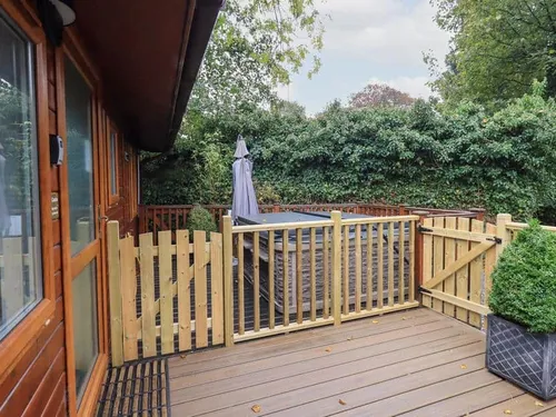 Lodge deck with hot tub behind wooden gate and potted shrub