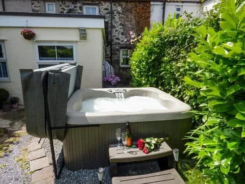 Cottage garden with hot tub and steps, champagne bottle and glasses on table