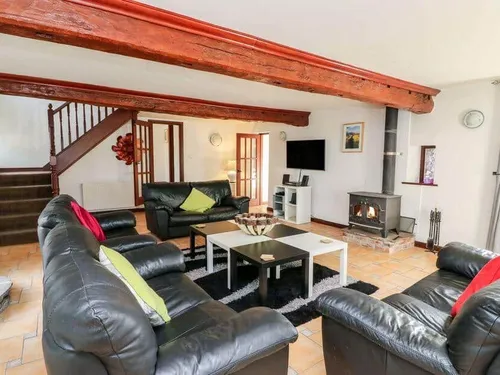 Lounge with leather sofas, wood-burning stove and exposed ceiling beam