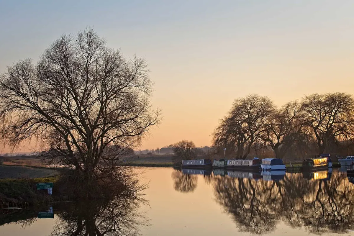 Sunset reflecting on the calm waters of the River Cam in the Cambridgeshire Fens.