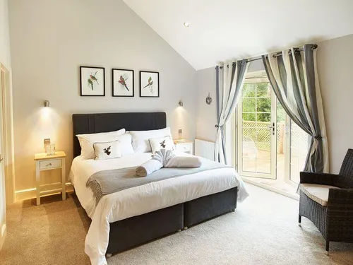 Lodge bedroom with double bed, wicker chair and patio doors with curtains