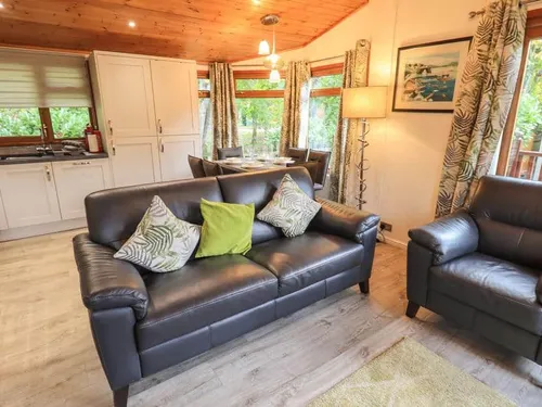 Lodge lounge with leather sofa, armchair and view of kitchen and dining table