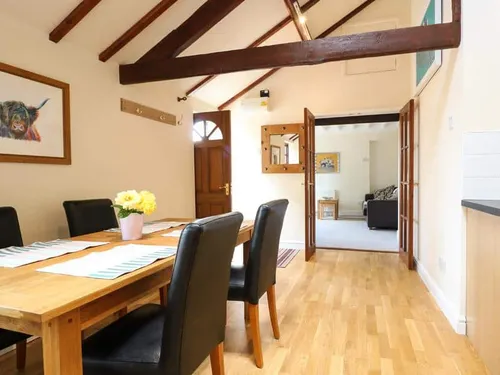 Cottage dining area with wooden table, black chairs and exposed ceiling beams