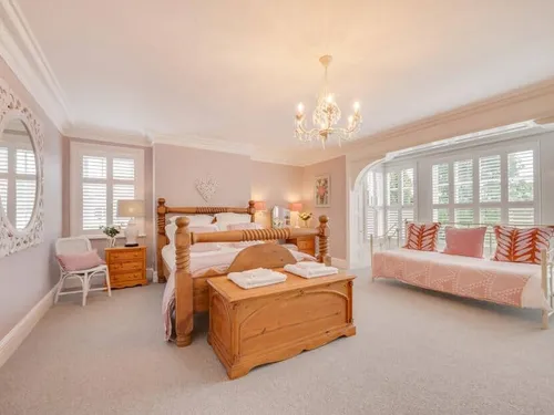 Bedroom with wooden bed frame and bay window with shutters