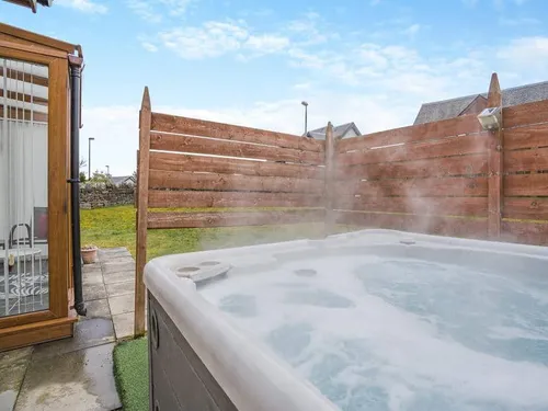 Cottage patio with hot tub and wooden privacy fence