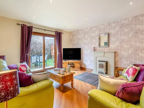 Cottage lounge with sofas, television, fireplace and sliding doors to garden patio