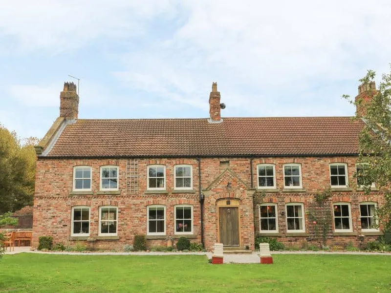 Copmanthorpe Hall brick cottage with large front lawn and two chimneys