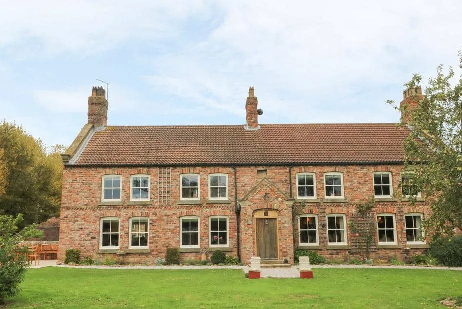 Copmanthorpe Hall brick cottage with large front lawn and two chimneys
