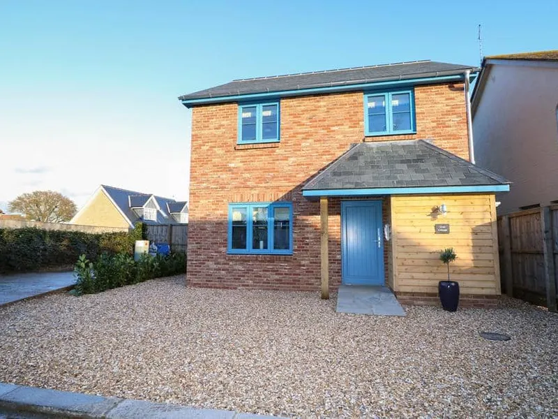 Crab Cottage exterior with red brick walls, blue windows, and gravel driveway