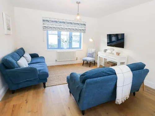 Cottage living room with two blue sofas and wall-mounted television