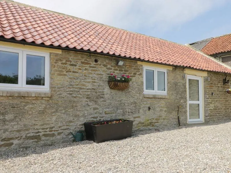 Stone exterior of Crabtree Cottage with red tiled roof and flower planters by the entrance.