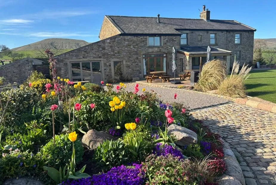 Stone Cuthbert Hill Farm cottage with colourful garden and cobbled path in countryside setting