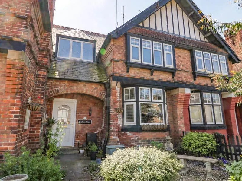 Destiny Rose cottage with red brick facade, bay windows and front garden