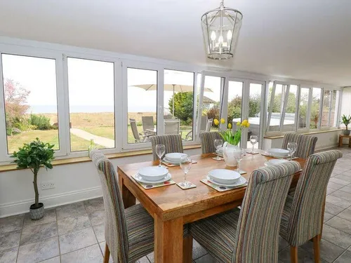 Cottage dining area with set table and large windows overlooking garden and patio