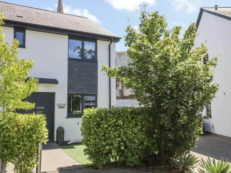 Driftwood with front garden and leafy trees by the entrance