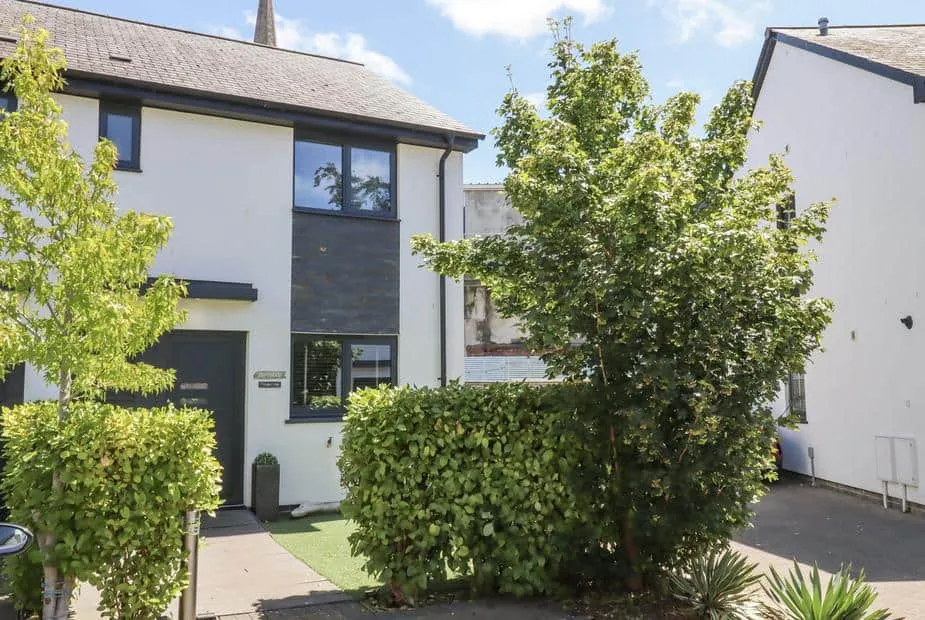 Driftwood with front garden and leafy trees by the entrance