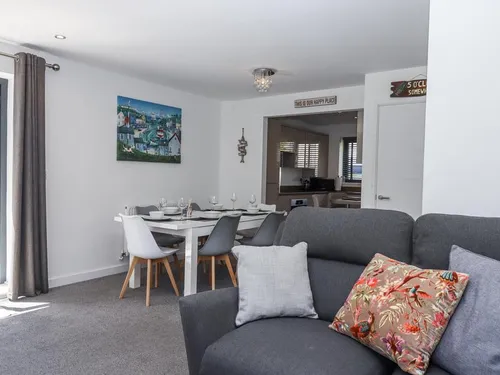 Cottage dining area with set table and grey sofa in the foreground