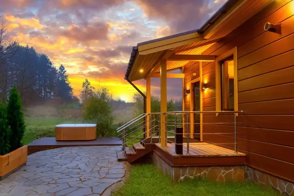Serene hot tub escape at a modern English cabin during a golden hour sunset.