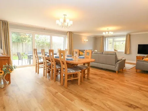 Cottage open-plan lounge and dining area with wooden table and grey sofas