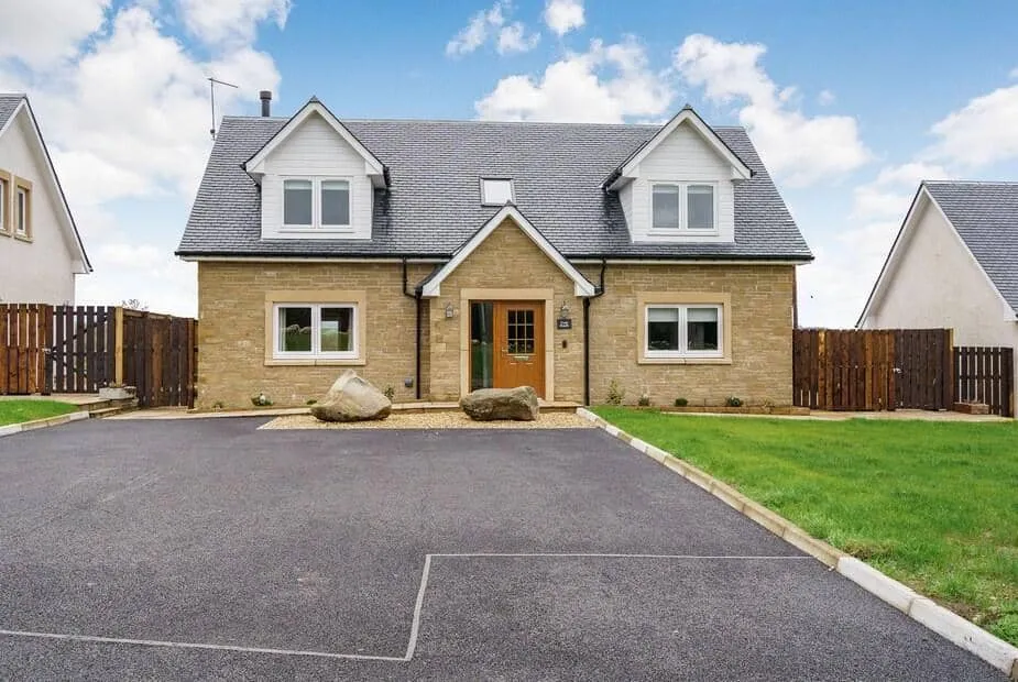 Fiadh Ruadh with gabled roof and driveway, fronted by two large stones