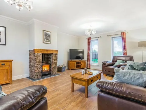 Living room with stone fireplace, leather sofas and wooden coffee table