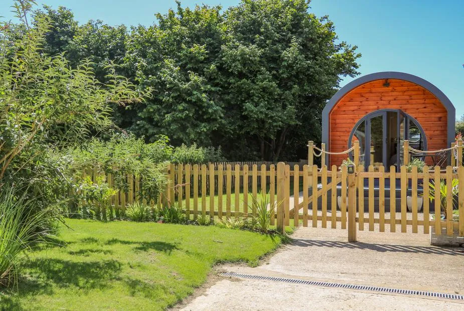 Filbert Pod wooden lodge with arched entrance and fenced garden area in front