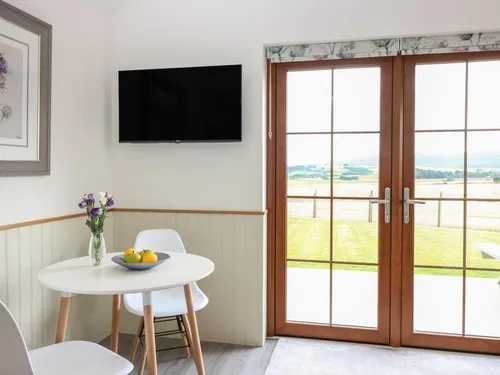 Cottage dining area with round table and French doors overlooking fields